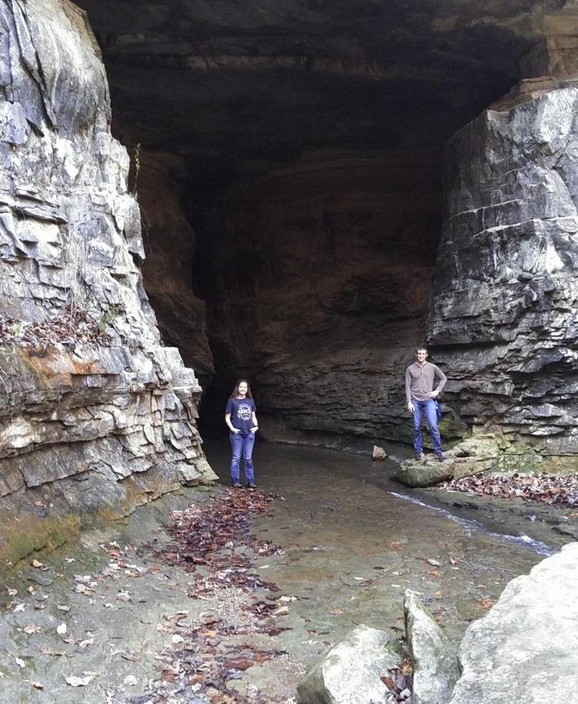 Two students posing near the entrance to a cave