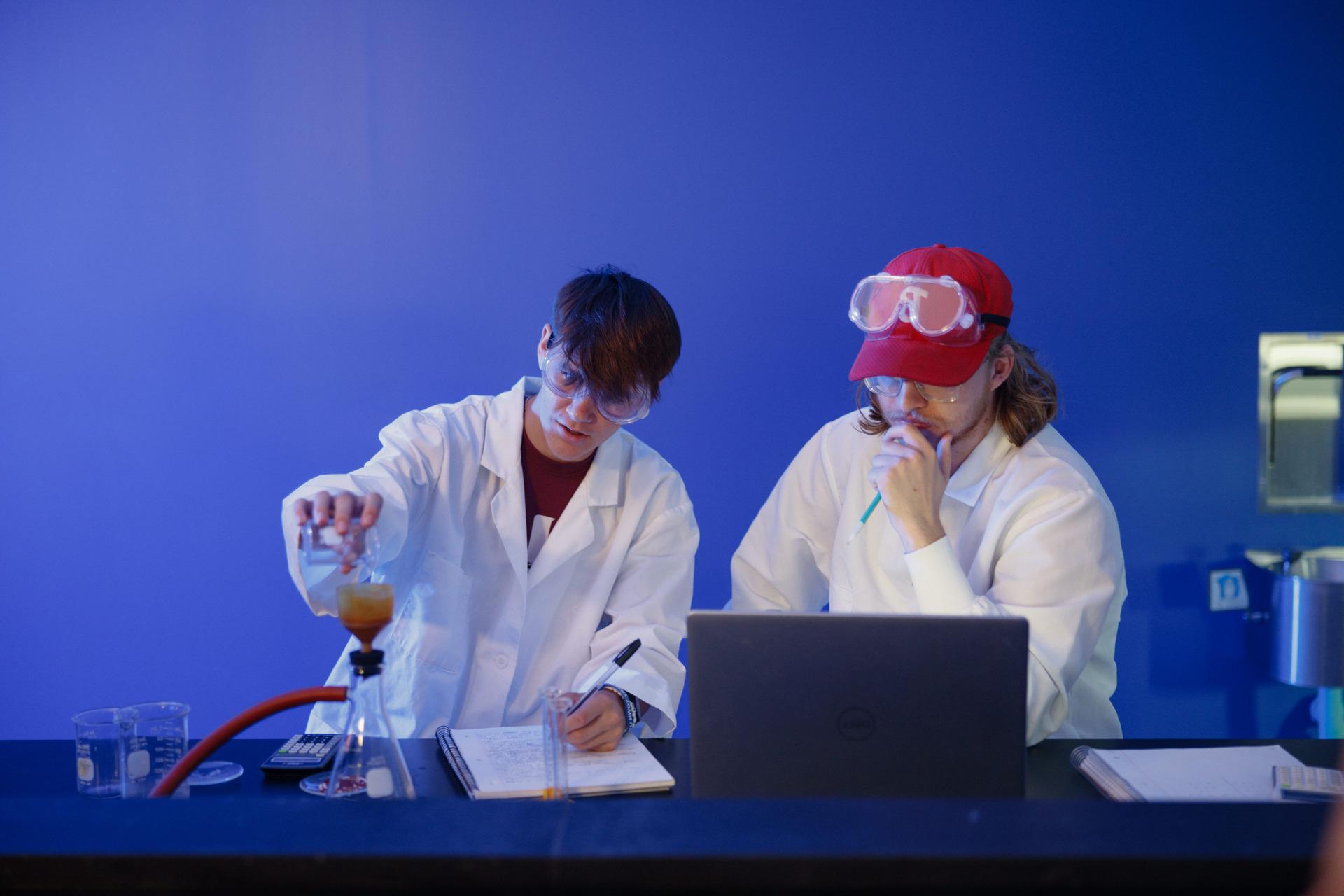 A chemistry teacher showing her student a cup with a green liquid inside