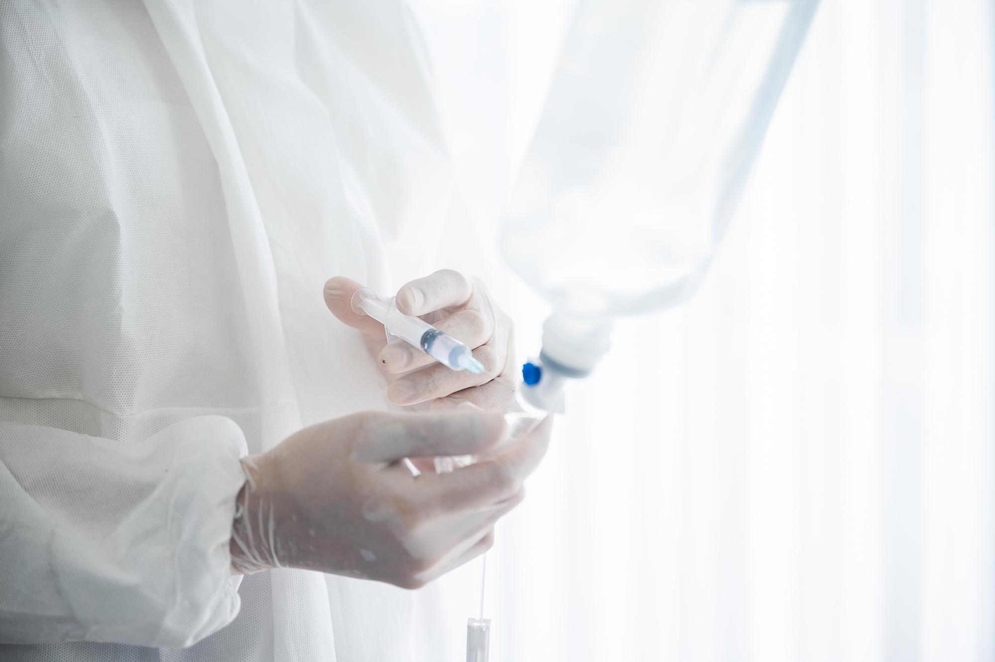 A doctor sticking a needle into a bag